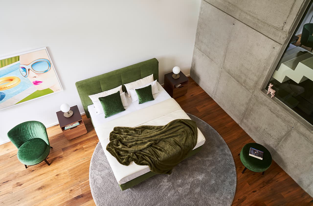 Helles Schlafzimmer mit grünem Polsterbett.